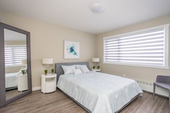 A bedroom with a large bed, a mirror, and a painting on the wall.